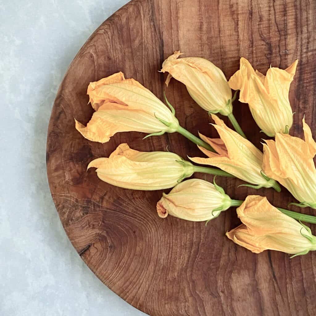 Närbild på skärbräda ARVID som har vackra zucchiniblommor på sig.