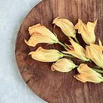 Närbild på skärbräda ARVID som har vackra zucchiniblommor på sig.