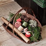 Jutesnöre i en korg omgiven av juldekorationer som tallkvistar, kottar och inslagningspapper.