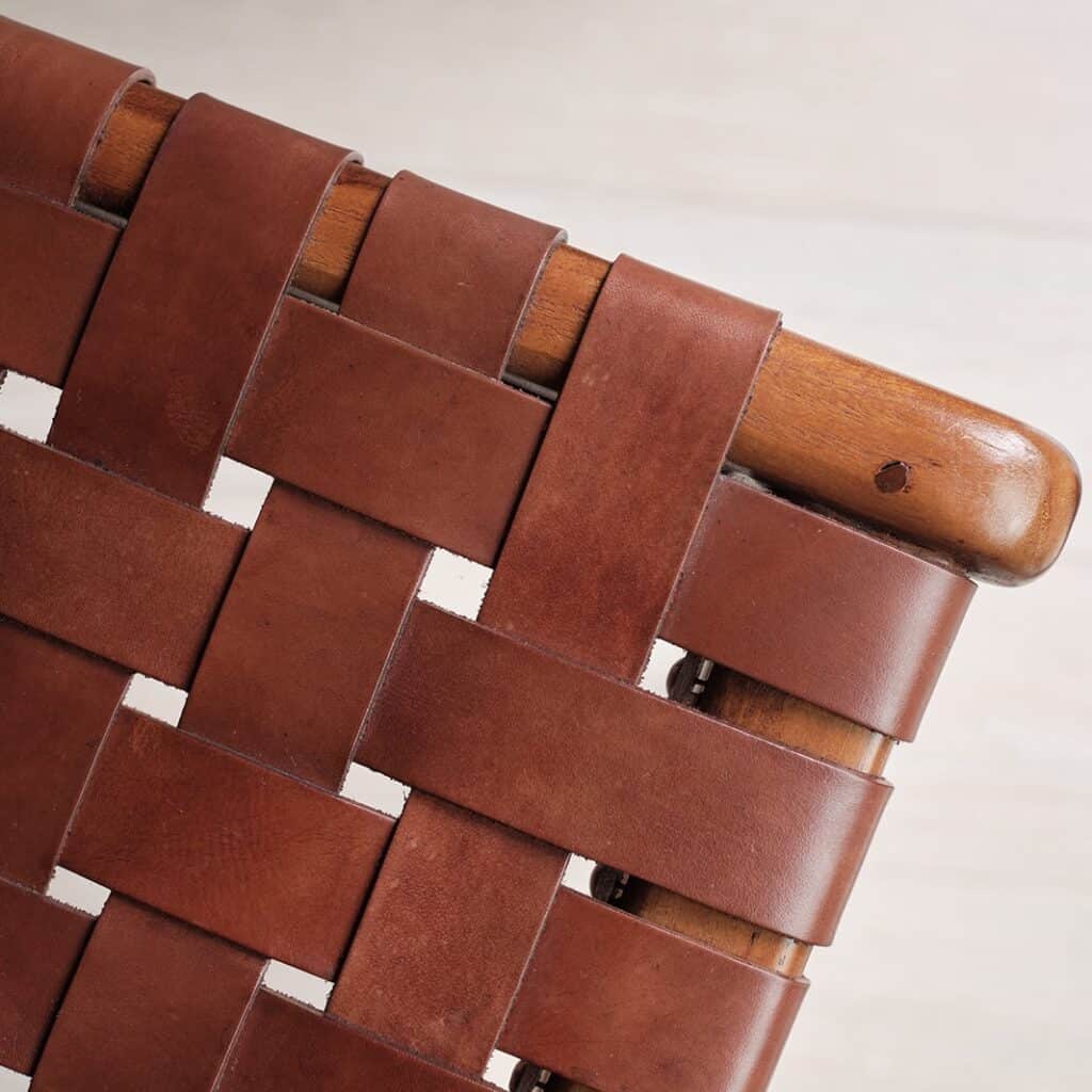 Närbild på flätad lädersits i konjak och teakram från Porto pall av Wikholm Form.