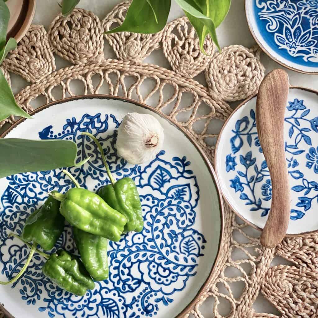 Bordstablett Doory från Nordal i jute med dekorativa tallrikar och grön paprika på en träyta.