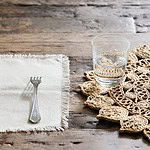 Detaljbild av bordstabletten Doory från Nordal med ett glas vatten och en gaffel på en rustik träyta.