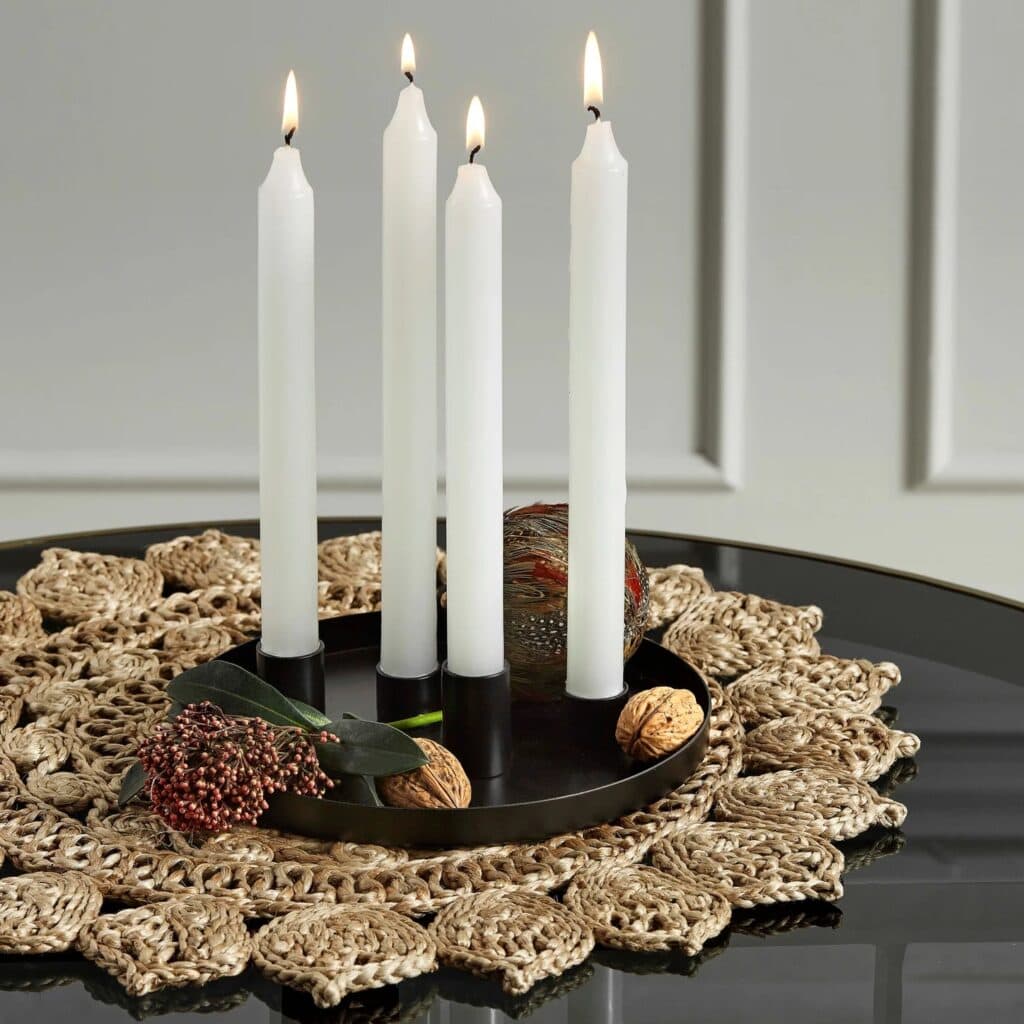 Bordstablett Doory från Nordal dekorerad med en svart ljusstake med fyra tända vita ljus och nötter.