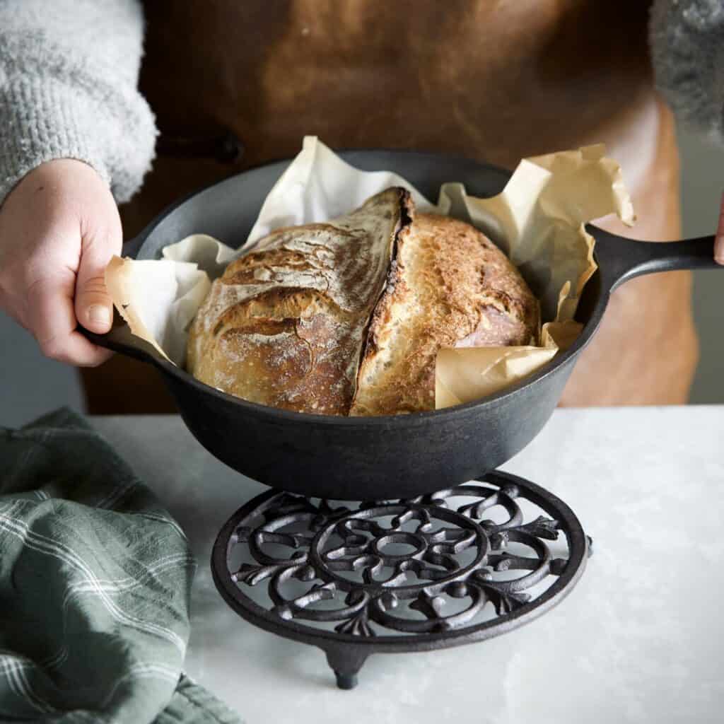 Grytunderlägget FREJ i gjutjärn från Affari of Sweden, placerat på ett träbord omgiven av gröna växter.