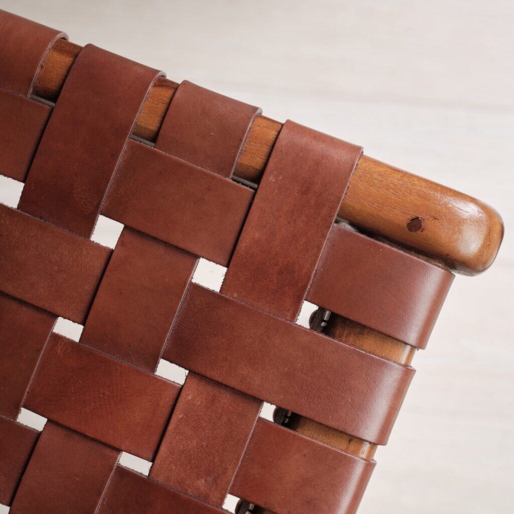 Närbild på flätat konjaksfärgat läder och trädetaljer på fåtöljen PORTO från Wikholm Form, som visar det hantverksmässiga utförandet och den robusta kvaliteten.