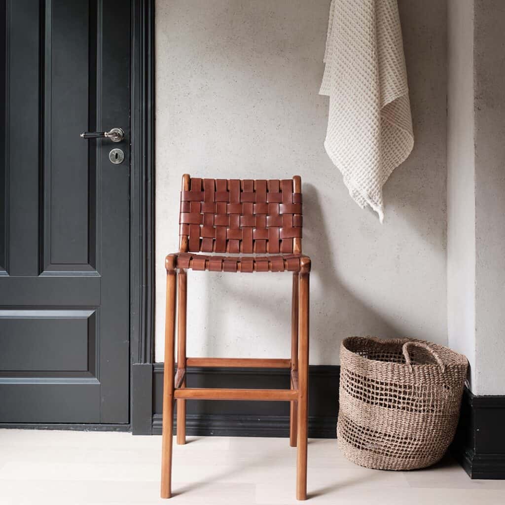 Barstol PORTO från Wikholm form placerad mot en vägg, med detaljbild på flätad kolädersits.