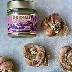 Burk med Gridelli Crema al Pistacchio bredvid nybakade pistagefyllda bakverk, pudrade med florsocker.