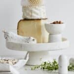 Kakfat i vit marmor från Nordal med ost, chark och mandlar – perfekt för servering.