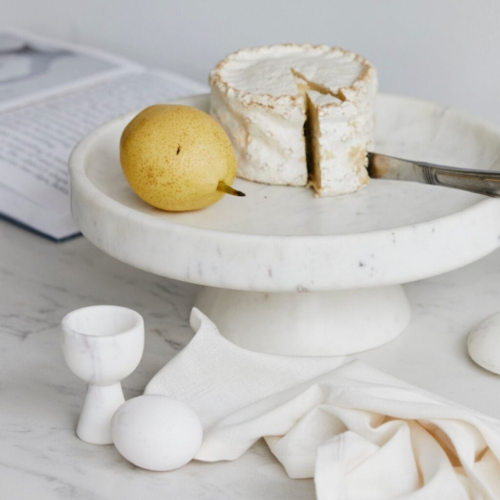 Kakfat i vit marmor från Nordal med päron och ost – stilren servering på marmorbord.