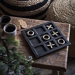 Luffarschack GLOBETROTTER i järn från Affari of Sweden i svart och guldfärg, placerat på ett rustikt träbord med kaffekoppar och pepparkakor i bakgrunden.