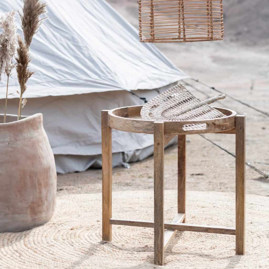 Bali brickbord i naturträ med rottingdetaljer, placerat på en utomhusmatta bredvid stora krukor.