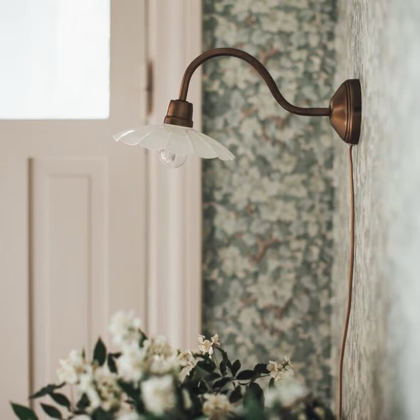 Vägglampa Gustav vit och antik mässing på vägg med blommig tapet