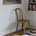 Bistrostol i björkträ i klassisk design placerad vid bokhylla i vardagsrum