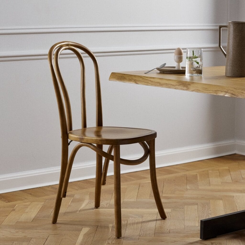 Klassisk bistrostol i björkträ vid matbord i ljust kök