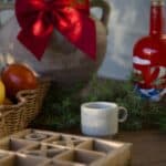 Espressomugg GRAINY i stengods på ett juligt stilleben med korg, frukt och grön kvist på träbord.