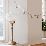 VALTER bordslampa från Strömshaga i en stilren interiör med dekorativ mässingsfot och vit opalglasskärm.