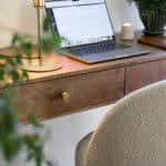 Konsolbord BETTON i mangotra med laptop, lampa och grona vaxter – detaljbild i varm hemmiljo.