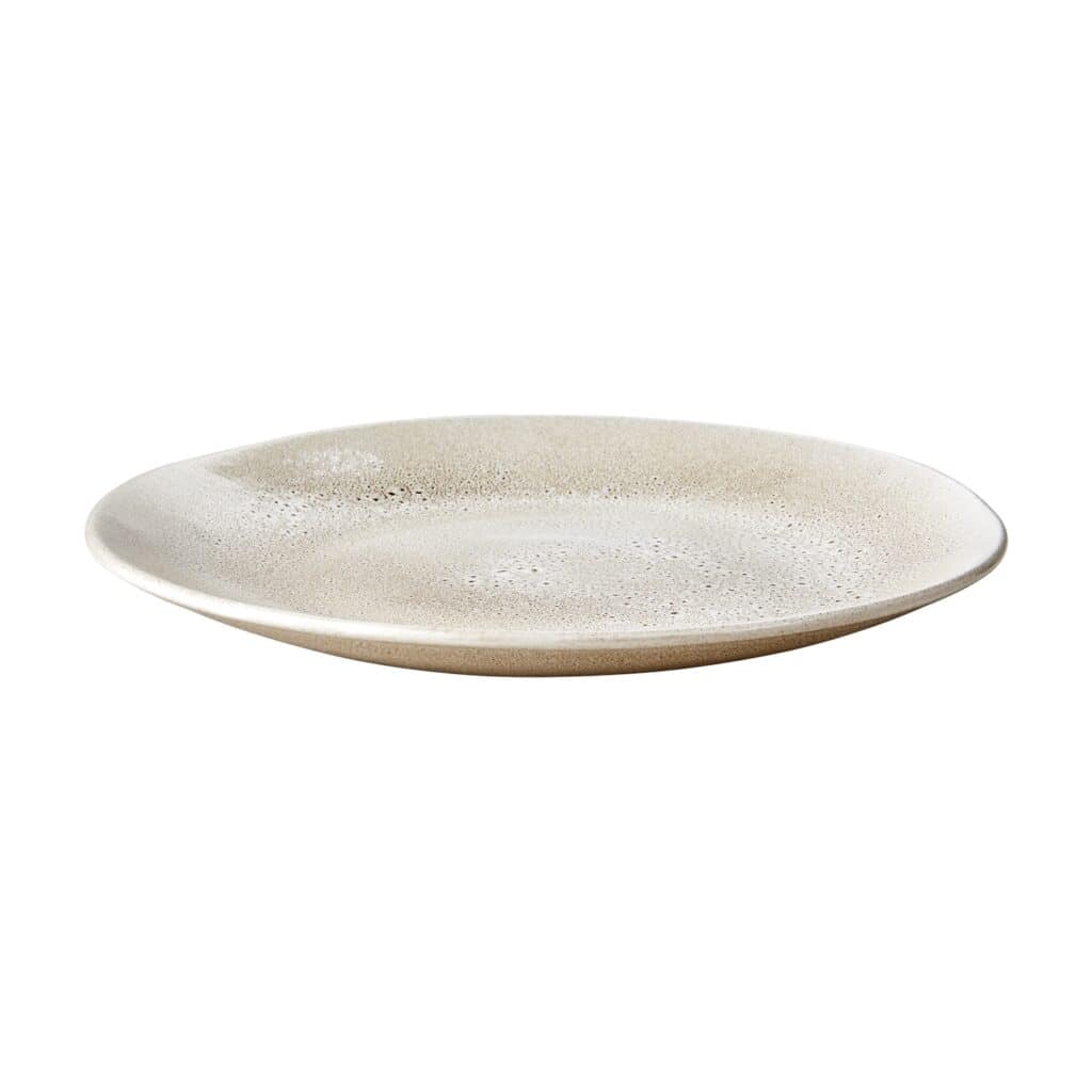 En beige tallrik från serien Annabelle av Affari of Sweden, fotograferad i profil mot en vit bakgrund. Tallriken har ett subtilt prickigt mönster.