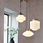 Tre taklampor därav en är taklampa VALTER. Taklamporna har olika former av opalglas i ett rum med en vas med blommor i bakgrunden.