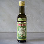 Flaska av Gridelli ekologisk olivolja med smak av basilika, fotograferad på en marmoryta.