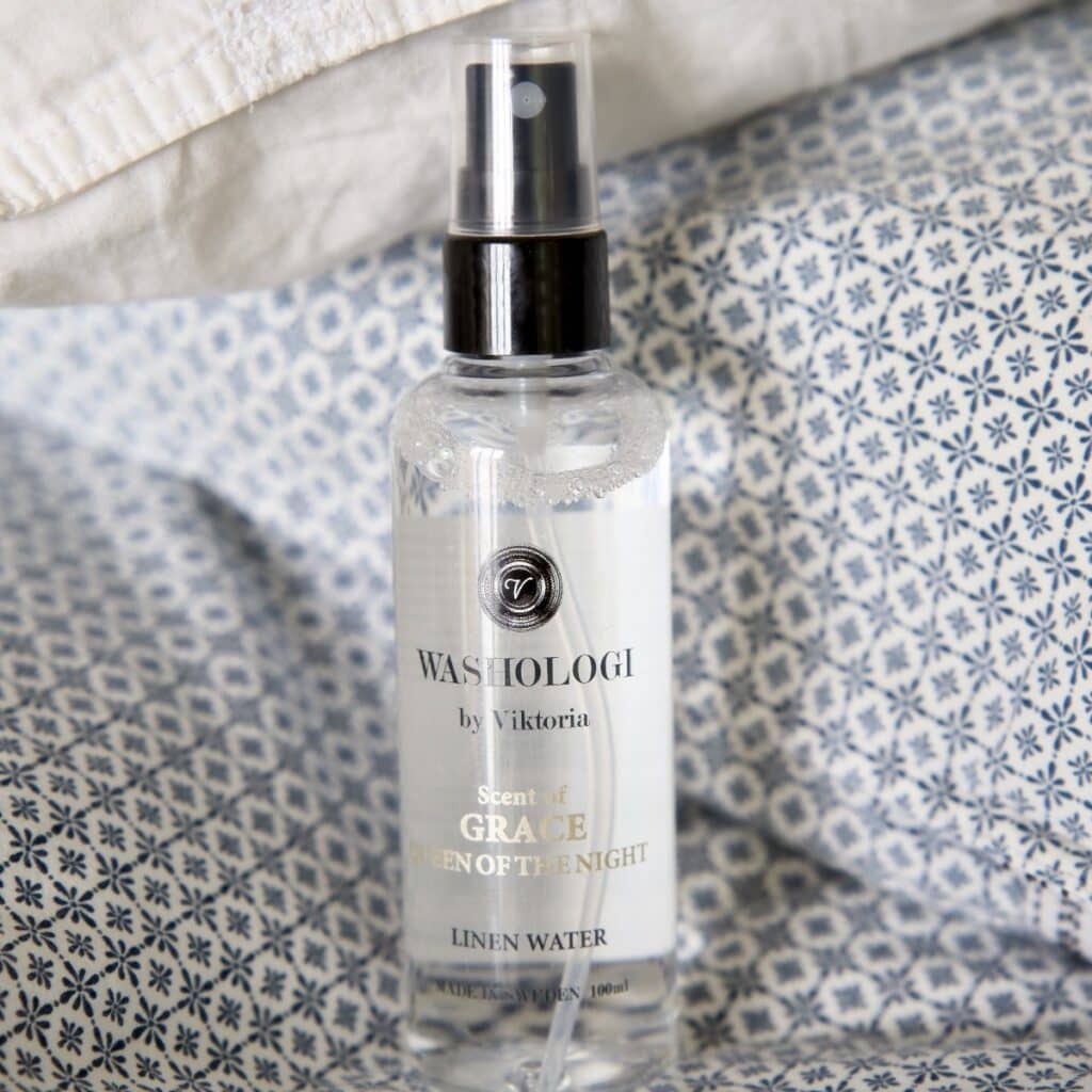 Washologi linnevatten Grace på en bädd av blå- och vitmönstrade tyger.