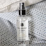 Washologi linnevatten Grace på en bädd av blå- och vitmönstrade tyger.