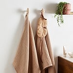 Två BASU krokar från Nordal med handdukar och accessoarer hängande på en vägg.