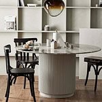 ERIE matbord uppställt i en matsal med bokhyllor i bakgrunden och svarta trästolar runt bordet, dekorerat med en lampa och frukosttillbehör.