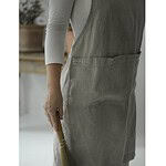 Närbild av ett linneförkläde med två fickor, bärs av en person i ett minimalistiskt hem.