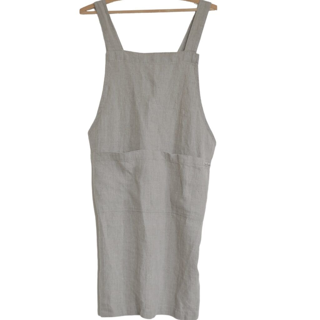 Linneförkläde som hänger på en galge, sett framifrån.