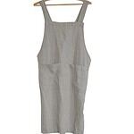 Linneförkläde som hänger på en galge, sett framifrån.