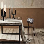 Vintagebord dukat med svarta ljusstakar och en linnefilt, stående i ett modernt vardagsrum med beige väggar och träplankgolv.