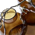 Närbild av bärnstensfärgade glasvaser med grenar som dekoration.