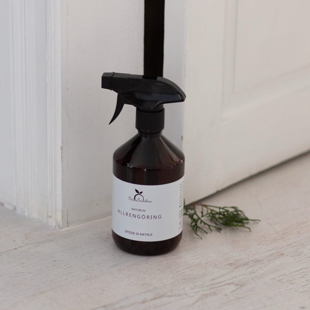 Ekologisk allrengöring Spezie di Natale från Gröna Gredelina, placerad på trägolv bredvid en dörr, redo för rengöring.