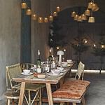 Dukat bord med ljusslinga i bambu från Madam Stoltz som hänger ovanför, skapar en mysig och inbjudande atmosfär i rummet.