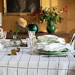 Elegant dukning med linneduken CLASSIC i vitt och grönt, dekorerat med blommor och gröna tallrikar.