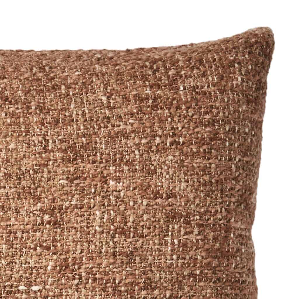 Närbild på strukturen på kuddfodralet NINA i korall och beige, som visar den grova och mjuka vävtexturen.