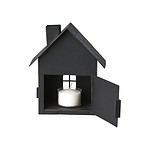 Svart ljuslykta i form av ett hus med öppna dörrar och ett tänd värmeljus inuti.