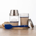Kilner Surdeg Starter Kit med glasburkar, blå silikonspatel och surdegsstarter. En bit bröd ligger på skärbrädan bredvid burkarna.