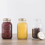 Tre Kilner konserveringsburkar fyllda med olika innehåll: tomatsås, äppelmos och kaffebönor, två med skruvlock och en öppen.