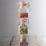 Tre staplade Kilner bygelburkar fyllda med kryddor – chili, kardemumma och senapsfrön – för praktisk och dekorativ förvaring i köket.