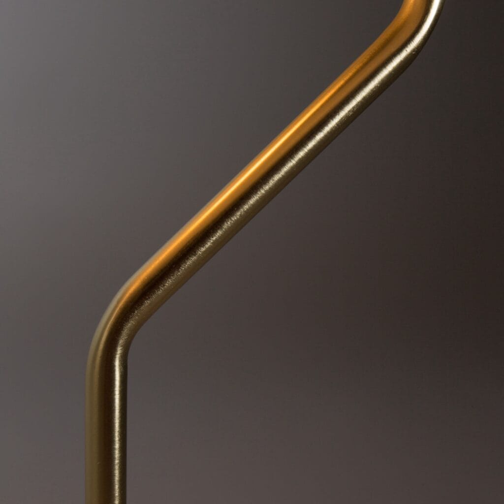 Detaljbild av den böjda mässingsstommen på bordslampan ECLIPSE från Dutchbone, som visar dess eleganta och moderna design.