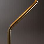 Detaljbild av den böjda mässingsstommen på bordslampan ECLIPSE från Dutchbone, som visar dess eleganta och moderna design.