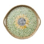 Rund bricka i mosaik med solrosmotiv i grönt, gult och blått, tillverkad med rottingkant och handtag, perfekt för servering eller som inredningsdetalj.
