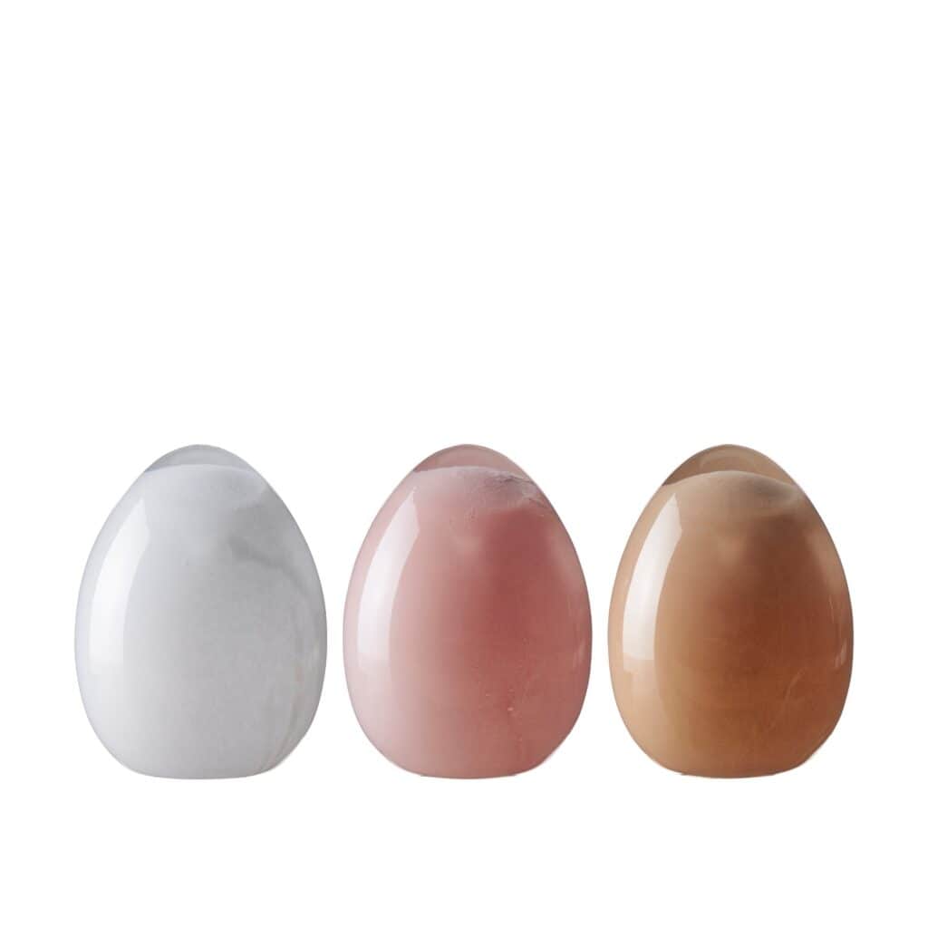 Tre dekorativa glasägg från Wikholm Form i färgerna vitt, rosa och sand, med en blank och elegant yta.
