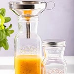 Kilner glasflaska fylld med apelsinsås och en rostfri tratt för enkel påfyllning.