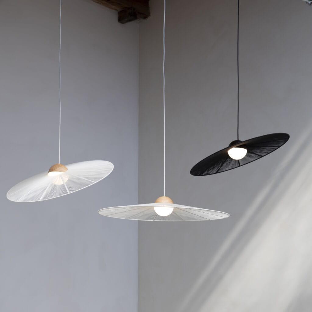 Tre taklampor Belle från Zuiver i olika färger (beige och svart) som hänger i en modern och stilren miljö med neutrala väggar.