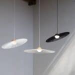 Tre taklampor Belle från Zuiver i olika färger (beige och svart) som hänger i en modern och stilren miljö med neutrala väggar.