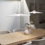 Närbild på två taklampor Belle från Zuiver i beige som hänger över ett ljust träbord i en minimalistisk matsal med neutrala och stilrena detaljer.