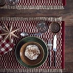 Julinspirerad dukning med ANNABELLE-tallrik i grönt stengods, röd bordsduk och keramikskål fylld med dessert.